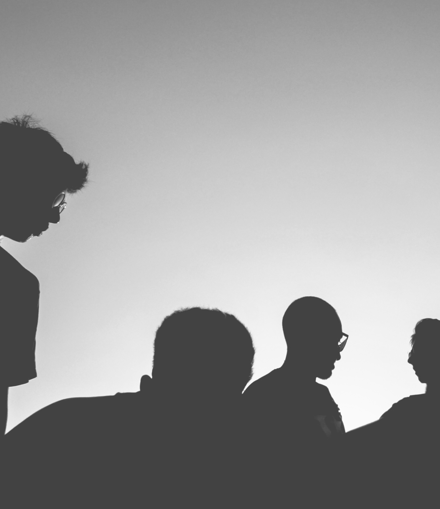 Grayscale silhouettes of a small crowd, masked to an organic edge